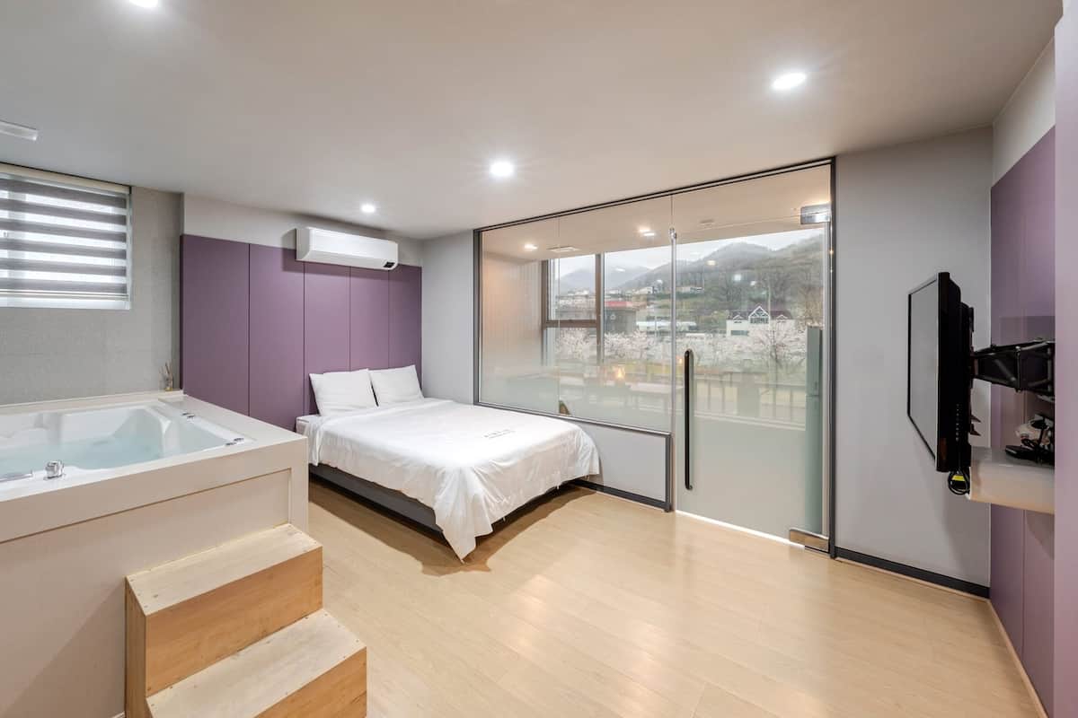 Un dormitorio moderno con un gran ventanal, una bañera y una cama.