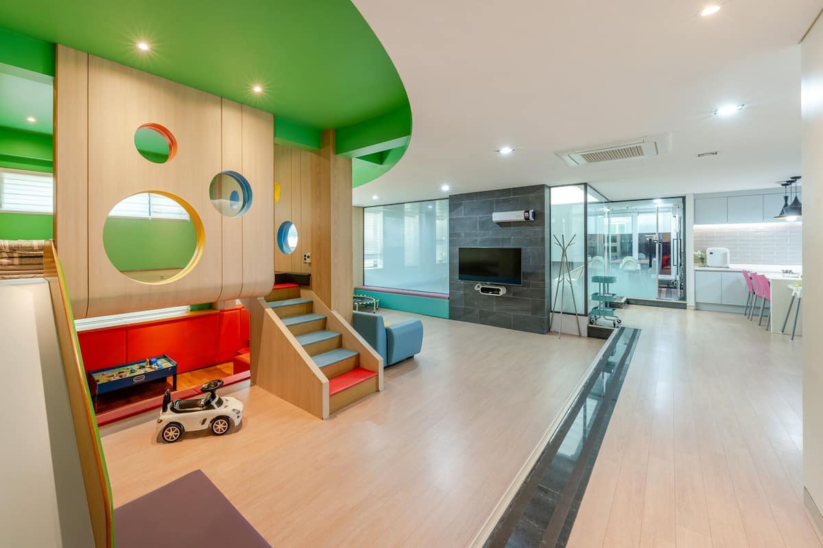 Un espacio de estar moderno con una escalera, una zona de juegos y una cocina.