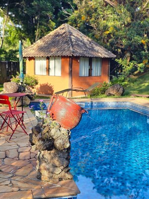 Una piscina al aire libre, sombrillas, sillones reclinables de piscina