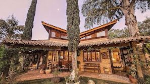 A traditional building with a tiled roof, wooden beams, and brick walls. It features a courtyard with a bench and potted plants. - Pousada Dharma Luz e Paz (Braganca Paulista)