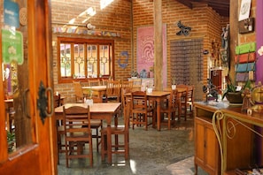 A rustic dining area with wooden tables and chairs, a brick wall, and various decorative items. - Pousada Dharma Luz e Paz (Braganca Paulista)