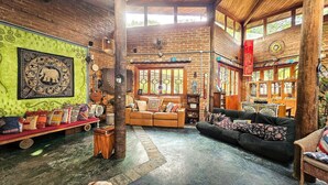 A rustic interior with exposed brick walls, a wooden ceiling, and a cozy seating area with a sofa and a bench. - Pousada Dharma Luz e Paz  (Braganca Paulista)