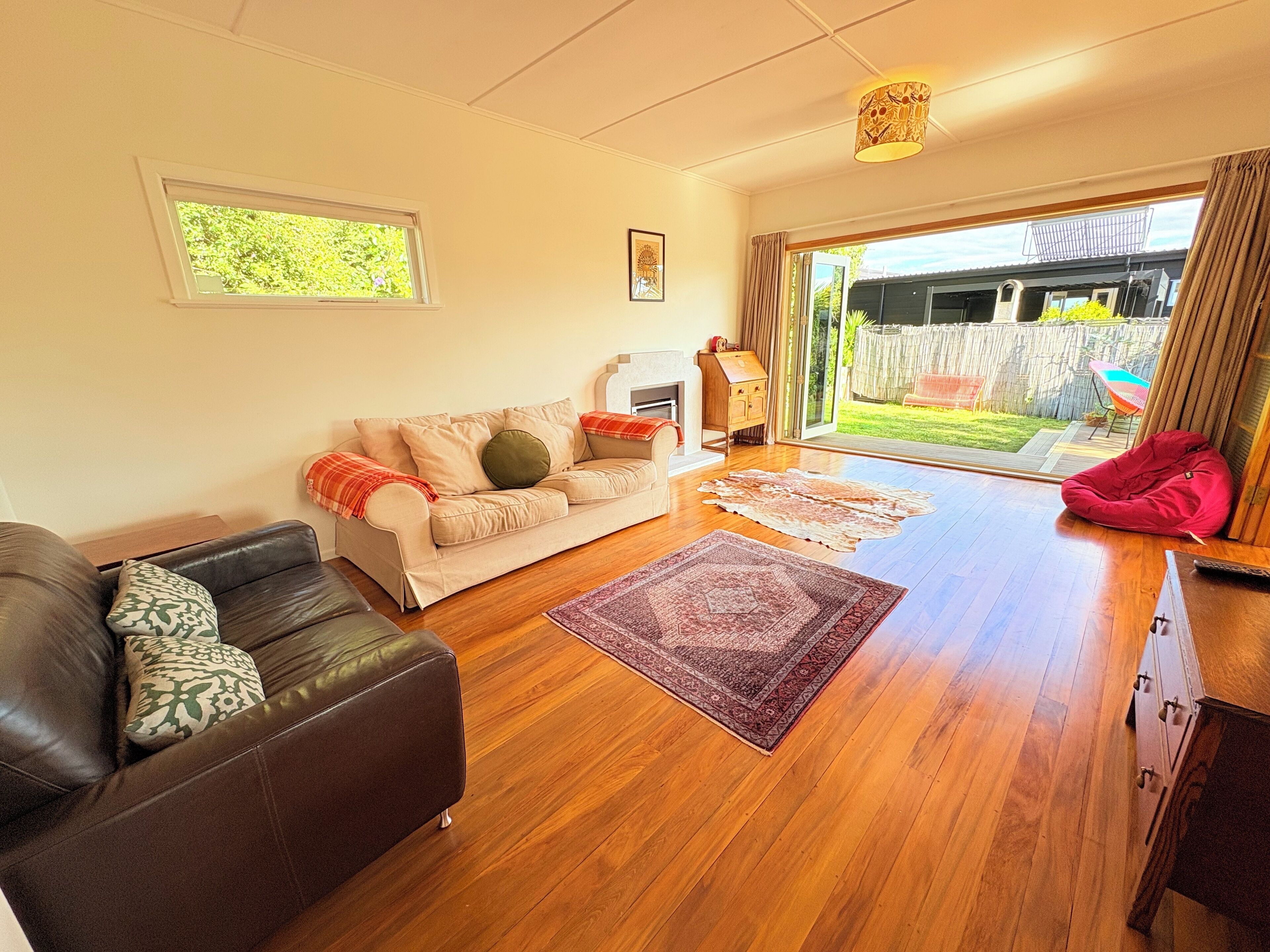 A living room with a sofa, a red bean bag, a rug, and a fireplace.