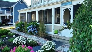 A two-story house with a covered porch, a balcony, and a sign that reads "The Lucky Guy."