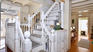 A staircase with white balusters and a wooden handrail leading to a landing with a small table and a chair.