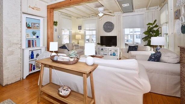 A cozy living room with a wooden ceiling, a television, a sofa, and a bookshelf.