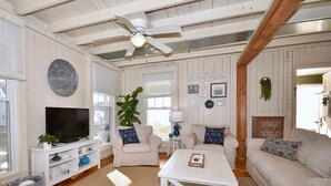 A cozy living room with a white TV stand, two sofas, a coffee table, and a ceiling fan.