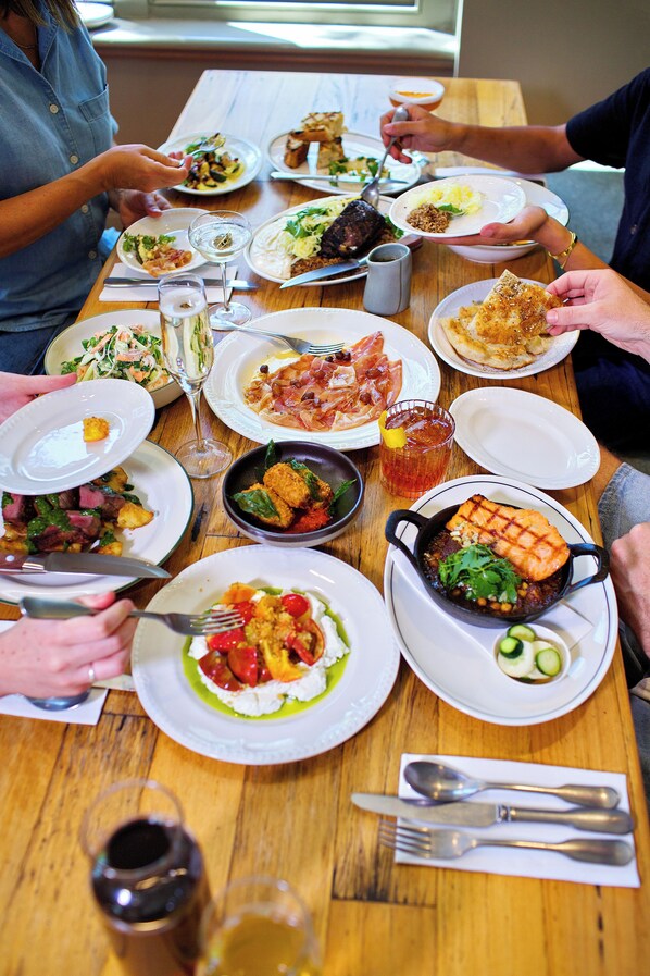 A dining table with various dishes, utensils, and glasses.