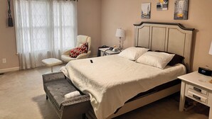 Une chambre à coucher avec un lit, une chaise, une table de chevet avec une lampe et un ventilateur de plafond.