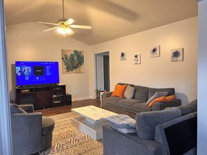 Relax in this stylish living room with a flat-screen TV, comfortable sofa, and decorative artwork.