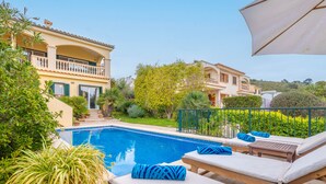 Un área de piscina con sillones de descanso y una pérgola.