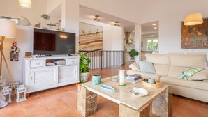 Una sala de estar moderna con televisor, muebles blancos, una mesa de centro y un sofá.