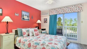 A bedroom with a bed, two bedside tables, a nightstand, a window with curtains, and a balcony.