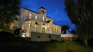A large, two-story house with a balcony and a tower-like structure on the roof.