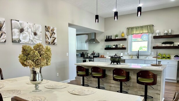 A modern kitchen with white cabinets, a central island with bar stools, and decorative wall art.