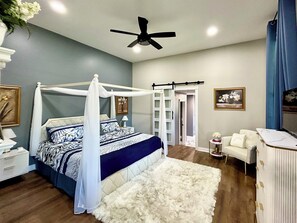 Cozy bedroom with a canopy bed, white rug, and a nightstand with a lamp.