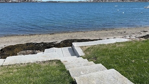 A stone staircase leading to a grassy area by a body of water. - Oceanfront Escape: Deck & Granite Steps to Shore (Harpswell)