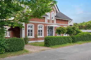 A red brick house with white trim, a front door, and a small porch. - Apartment 'Schlafmütze' with Shared Terrace, Shared Garden and Wi-Fi (Cuxhaven)