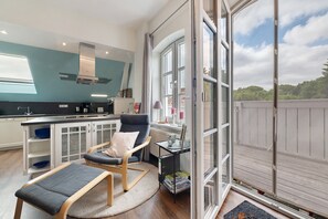 Ett modernt kök med matplats, ett stort fönster och utsikt över en träveranda.