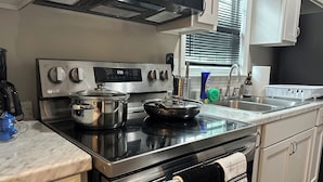 Une cuisine moderne équipée d’appareils électroménagers en acier inoxydable, d’une horloge numérique et d’une fenêtre avec des stores.