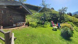 A log cabin, a grassy area, and a playground with slides.