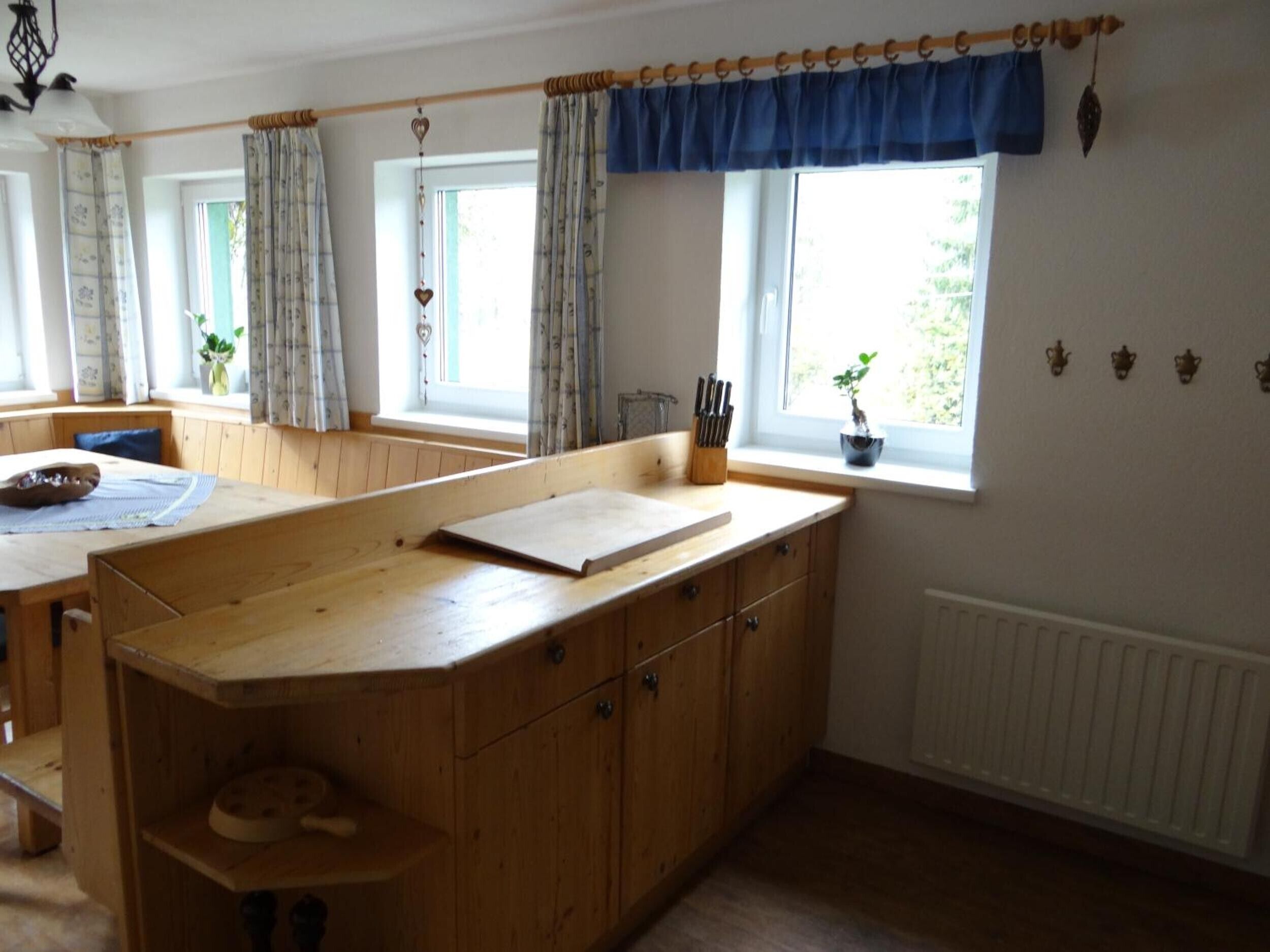 A kitchen with wooden cabinets, a countertop, and a window with curtains.