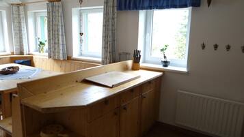 A kitchen with wooden cabinets, a countertop, and a window with curtains.