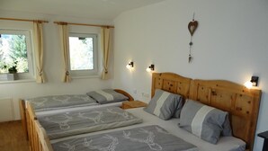 A double bed with a wooden headboard, two bedside tables, a wall-mounted light fixture, and a window with curtains.
