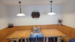 A wooden bench seating area with two tables and chairs, a wall-mounted clock, and pendant lighting.