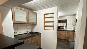 A kitchen with wooden cabinets, a black countertop, and a tiled backsplash. - Ski Lodge of the Skiclub Brilon with Mountain Views and Shared Terrace (Brilon)