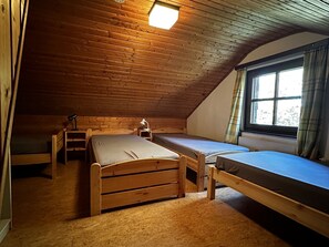A small, wooden-paneled attic room with two single beds, a desk, and a window with curtains. - Ski Lodge of the Skiclub Brilon with Mountain Views and Shared Terrace (Brilon)