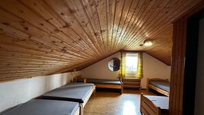 A room with wooden slatted ceilings, bunk beds, a small table, and a window with curtains. - Ski Lodge of the Skiclub Brilon with Mountain Views and Shared Terrace (Brilon)