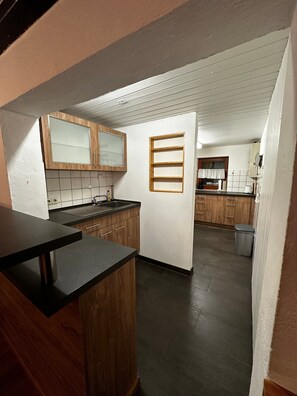 A kitchen with wooden cabinets, a black countertop, and a window with a curtain. - Ski Lodge of the Skiclub Brilon with Mountain Views and Shared Terrace (Brilon)
