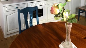 Eine Küche mit Herd, Spüle und einem Tisch mit Blumen in einer Vase.