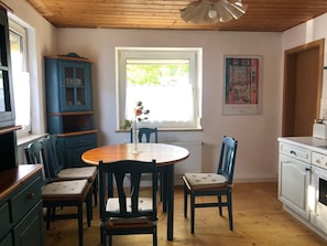 A kitchen with a round table, chairs, a window, a radiator, and a cabinet. - "My Holiday Home Rosenbusch 1" with Private Terrace, Garden and Wi-Fi (Kemmern)