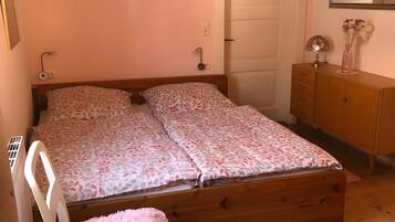A bedroom with a wooden bed, a white chair, a round rug, a dresser, and a mirror on the wall.