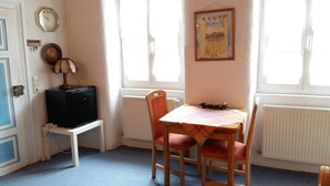 A room with a table, chairs, a radiator, a clock, and a small cabinet. - Holiday Apartment 'Sternenhof' with Wi-Fi (Breisach am Rhein)