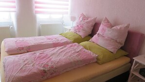 A double bed with floral bedding, a bedside table, and a window with blinds. - Holiday Apartment 'Sternenhof' with Wi-Fi (Breisach am Rhein)