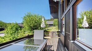 A deck with a glass-top table, wooden railings, and umbrellas.