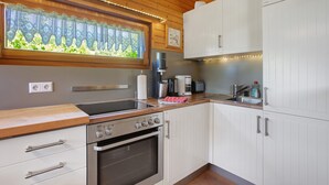 A modern kitchen with wooden cabinets, a built-in oven, and a window with a view of greenery.