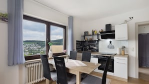 A modern kitchen with a dining area, a view of the city, and a window with curtains. - Holiday Apartment 'Zum Hasen' with Mountain View, Private Terrace and Wi-Fi (Meschede)