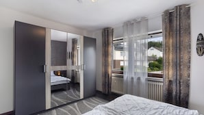 A bedroom with a bed, a wardrobe, a mirror, and a view of the outside. - Holiday Apartment 'Zum Hasen' with Mountain View, Private Terrace and Wi-Fi (Meschede)
