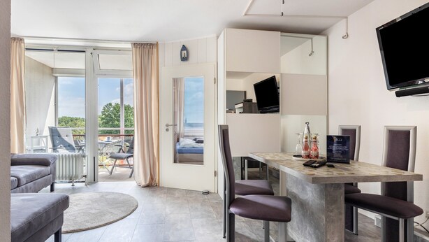 Una habitación moderna con comedor, televisor y vistas al exterior.