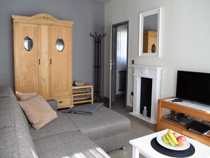 Ein Wohnzimmer mit einer Couch, einem Fernseher, einem Kamin und einem Holzschrank.