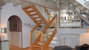 Un vaste espace de vie agrémenté d’un escalier en bois, d’une cheminée et d’un coin salon confortable.