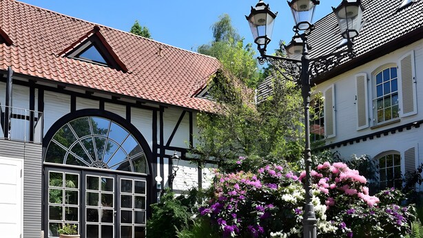 Un edificio tradicional con tejado de tejas, un amplio ventanal de arco y una farola.