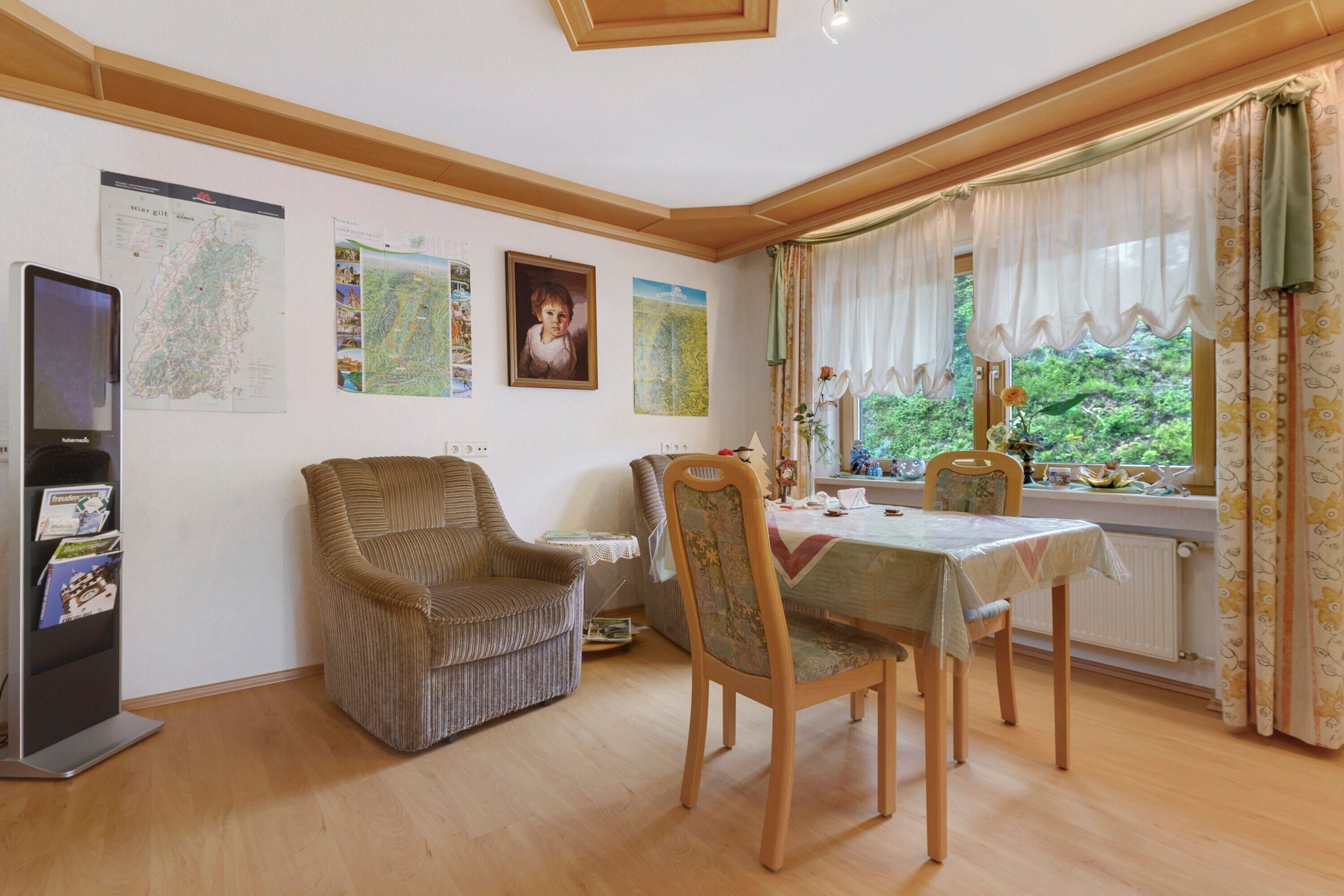 Un comedor con una mesa, sillas, una estantería y una ventana con cortinas.