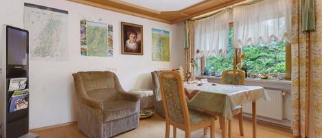 Un comedor con una mesa, sillas, una estantería y una ventana con cortinas.