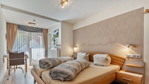 A modern bedroom with a large bed, a desk, and a chair. - Gästehaus Gerda: Double Room 3 with Mountain View, Private Balcony and Wi-Fi (Bad Peterstal-Griesbach)