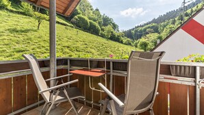 A balcony with two chairs and a table, overlooking a grassy hillside. - Gästehaus Gerda: Double Room 3 with Mountain View, Private Balcony and Wi-Fi (Bad Peterstal-Griesbach)